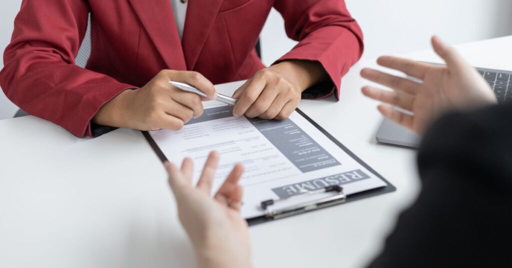 Person discussing form details in office meeting showing real-life example of constraint on bavayllo in structured decision making