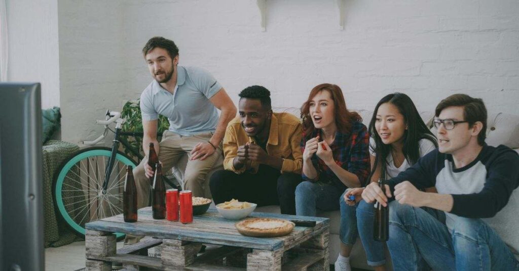 Friends watching TV, cheering with snacks and drinks