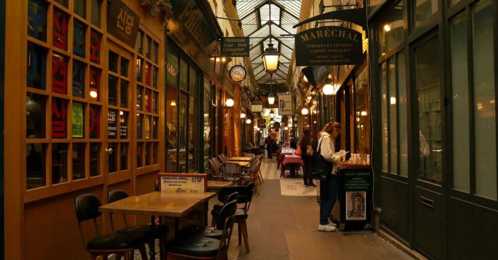 Cozy Paris covered street with cafés and warm night lights inside passage arcade